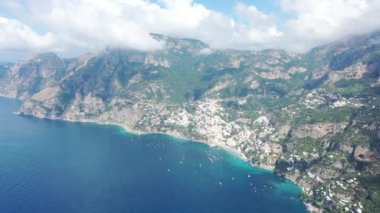 Positano, İtalya 'nın havadan görünüşü, Akdeniz' in yukarısından Amalfi Sahili boyunca mavi gökyüzü ve yazın bulutlarla dönüyor (4K)