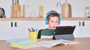 Akıllı çocuk tablet hakkında online ders dinliyor kulaklık takıyor Spbas. Evde eğitim görmüş çocuk gözetimi.