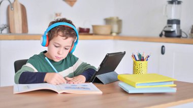 Akıllı çocuk tablet hakkında online ders dinliyor kulaklık takıyor Spbas. Evde eğitim görmüş çocuk gözetimi.