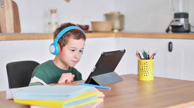 Akıllı çocuk tablet hakkında online ders dinliyor kulaklık takıyor Spbas. Evde eğitim görmüş çocuk gözetimi.