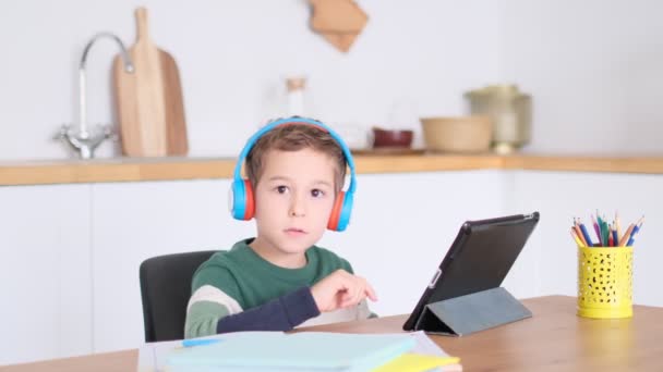 Милый маленький мальчик смотрит мультики на планшете — стоковое видео