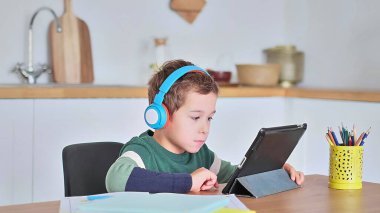 Akıllı çocuk tablet hakkında online ders dinliyor kulaklık takıyor Spbas. Evde eğitim görmüş çocuk gözetimi.