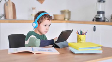 Akıllı çocuk tablet hakkında online ders dinliyor kulaklık takıyor Spbas. Evde eğitim görmüş çocuk gözetimi.