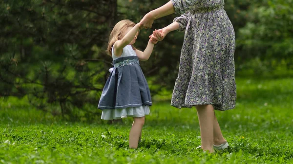 一个可爱的小女孩和她的妈妈在散步。妈妈和小女孩在花园里玩耍。与女儿拥抱并在户外玩得开心的女人. — 图库照片