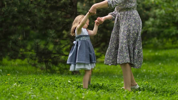 一个可爱的小女孩和她的妈妈在散步。妈妈和小女孩在花园里玩耍. — 图库照片