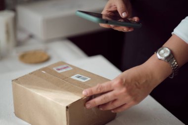 Dükkanında duran küçük işletme sahibi başvuru formunu akıllı telefondan ayarlıyor. çevrimiçi mağaza satıcı girişimcisi paketleme paketi posta kutusu hazırlama teslimat paketi.
