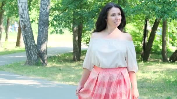 Mujer atractiva de mediana edad con cabello oscuro, disfrutando de la naturaleza en el bosque. Caminando entre los árboles a la luz del sol. mujer segura de sí misma — Vídeos de Stock