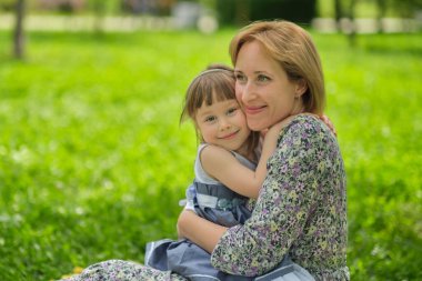 Yan manzara yakın çekim mutlu tatlı kız kucaklayan anne kucaklaşması. Mutlu aile kavramı. Mutlu gülümseyen çocuk portresi yaz günü annesine sarılıyor..