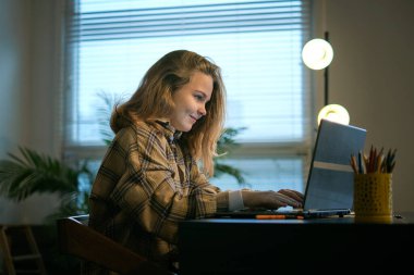 Genç kız yatak odasındaki bir masada ödev yapıyor. Genç kız öğrenci notlar yazıyor internetten video izleyip bilgisayardan öğreniyor. Uzaktan öğrenme kursu video konferansı pc çağrısı.