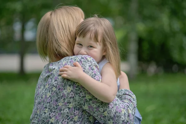 侧视近距离拍摄快乐可爱的女儿抱着拥抱妈妈.幸福家庭的概念。夏天的一天，孩子们拥抱着妈妈，面带微笑 — 图库照片