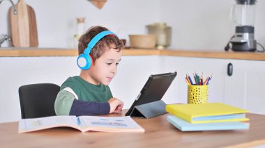Akıllı çocuk tablet hakkında online ders dinliyor kulaklık takıyor Spbas. Evde eğitim görmüş çocuk gözetimi.