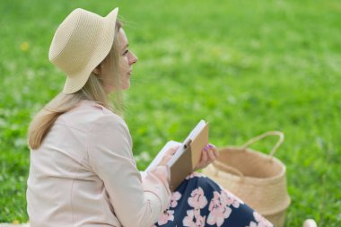 Dışarıda çimlerin üzerine kalem yazan bir kadın..