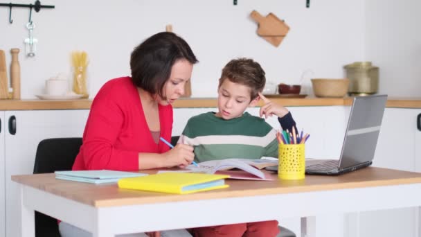 Eine Privatlehrerin hilft der jungen Studentin bei den Hausaufgaben am Schreibtisch im hellen Kinderzimmer. Mutter hilft Sohn beim Unterricht. Hausaufgabenbetreuung, Hausunterricht. — Stockvideo