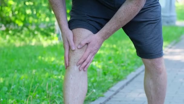 Lo sportivo si sta dimenando dal dolore alla gamba, si è ferito durante l'allenamento in strada. Teneva male il ginocchio. — Video Stock