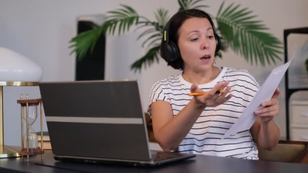 Jovem usa fone de ouvido conferência chamando no laptop conversa com professor on-line estudando, trabalhando em casa . — Vídeo de Stock