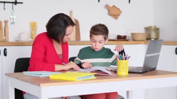 Žena soukromé lektorka pomáhá mladému studentovi s domácím úkolem na stole v jasném dětském pokoji. Matka pomáhá synovi s lekcemi. domácí výuka, domácí výuka. — Stock video