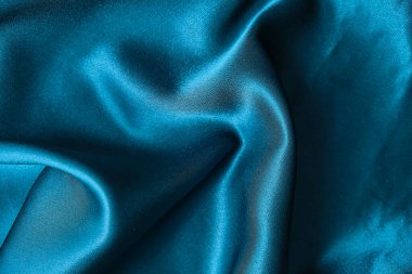 Mavi ipek kumaş ve avludan gelen döşeme kumaşı. Mavi saten, ipek kumaş, dalga, kumaş. Güzel tekstil arkaplanı. Yakın plan. Üst görünüm