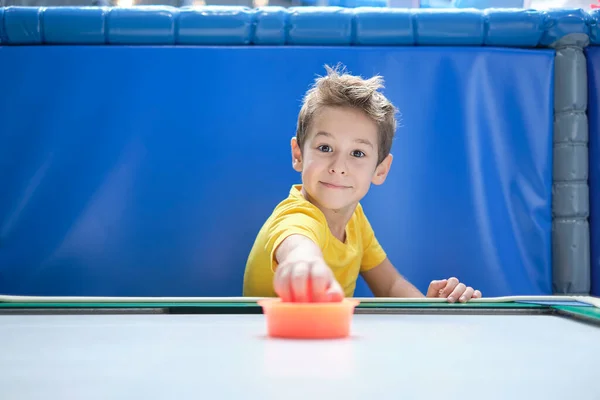 Jongen intensief en enthousiast tafelhockey spelen.. Een kind dat heeft gewonnen zijn air hockey wedstrijd, met een rode hamer in zijn hand. — Stockfoto