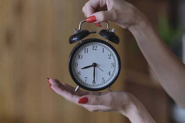Kırmızı manikürlü kadın elleri siyah bir çalar saat tutuyor. zaman yönetimi kavramı — Stok fotoğraf