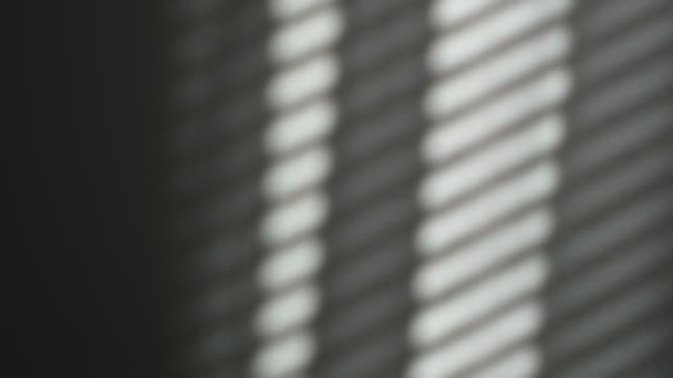 Morgensonne erhellt den Raum, Schatten überlagern sich. Spiegelung der Jalousien an der Wand, gestreifte Schatten. Langsame Bewegung der Vorhänge vom Wind — Stockvideo