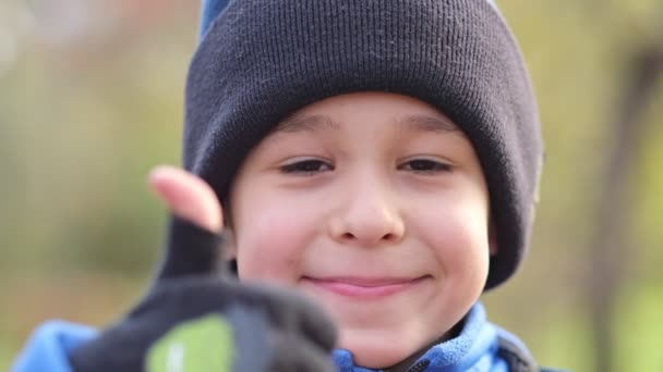 Portrét šťastně se usmívajícího chlapečka v klobouku. Dítě zvedá palce na kameru. Mladý chlapec portrét úsměv a dávat pozitivní gesto — Stock video