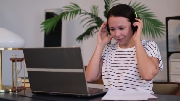 Jovem usa fone de ouvido conferência chamando no laptop conversa com professor on-line estudando, trabalhando em casa . — Vídeo de Stock