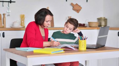 Bayan özel öğretmen, parlak çocuk odasında genç öğrencilere ödevlerinde yardım ediyor. Anne oğlunun ders almasına yardım eder. Evde eğitim, ev dersleri..