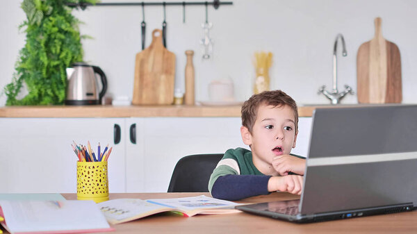 мальчик учится в онлайн-школе, показывая ответ на вопрос по видеосвязи