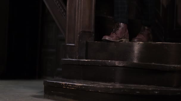 Męskie stopy schodzą po drewnianych, czarnych schodach starego domu. ciemny, ponury dom — Wideo stockowe