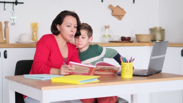 Vrouwelijke privé-leraar helpt jonge student met huiswerk aan bureau in heldere kinderkamer. Moeder helpt zoon om lessen te volgen. thuisonderwijs, huislessen. — Stockvideo