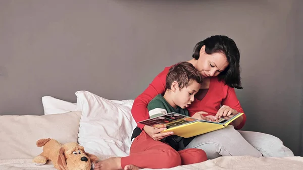 Mère et fils lecture livre ensemble sur le lit — Photo