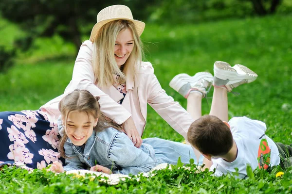 Семья проводит выходные на природе. счастливая семья на открытом воздухе на траве в парке. Мать носит сына и дочь, когда они играют в парке. мягкий фокус — стоковое фото