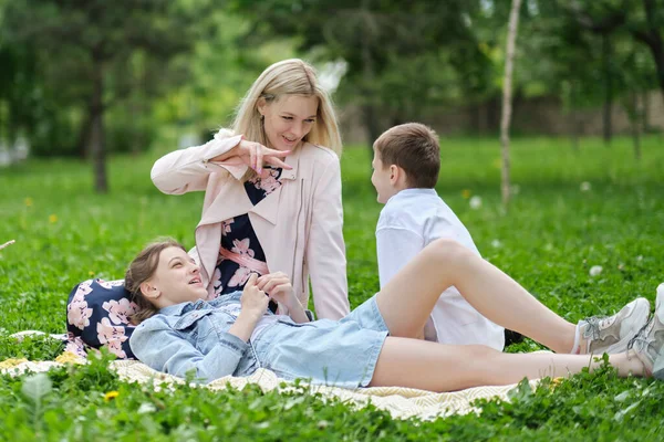 Família passa o fim de semana na natureza. família feliz ao ar livre na grama em um parque. Mãe carregando filho e filha como eles brincam no parque. foco suave — Fotografia de Stock