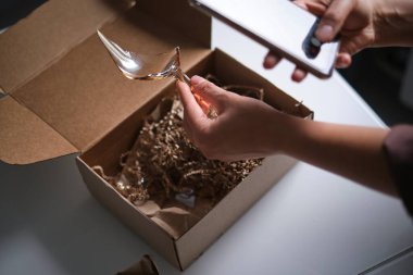 Kadın dükkandan bir teslimat kutusunu açıyor ve kırık bir cam buluyor. Teslimat sırasında paketlenmemiş bir eşya çöktü