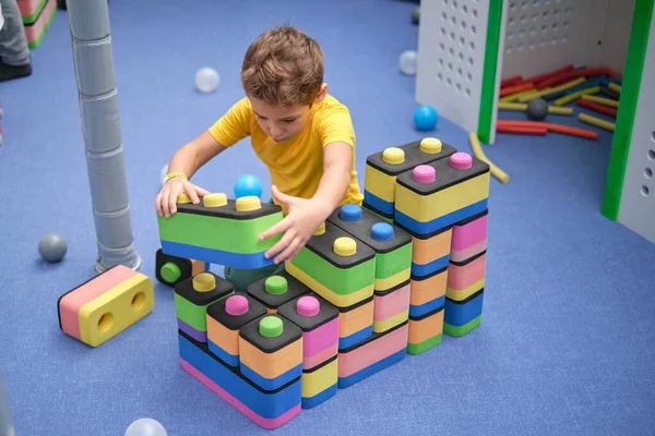 Маленький мальчик использует блоки здания ракеты. Концепция обучения и развития детей. senory room, independent play — стоковое фото