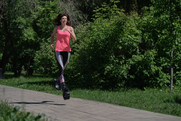 Wanita cantik berjalan di sepanjang jalan di taman, kaki di sepatu melompat kanggo. Wanita melatih Kangoo Melompat — Stok Foto