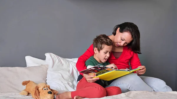 Mother and son reading book together on bed — Stock Photo, Image
