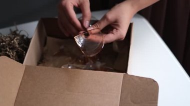 Kadın dükkandan bir teslimat kutusunu açıyor ve kırık bir cam buluyor. Teslimat sırasında paketlenmemiş bir eşya çöktü