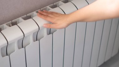 Kadınlar radyatöre dokunur. Sıcak radyatör, ısıtma mevsimi konsepti
