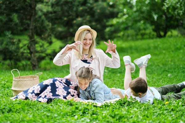 Rodzina spędza weekend w przyrodzie. szczęśliwa rodzina na zewnątrz na trawie w parku. Matka Nosząca Syna i Córkę Jak Grają W Parku. miękkie skupienie — Zdjęcie stockowe