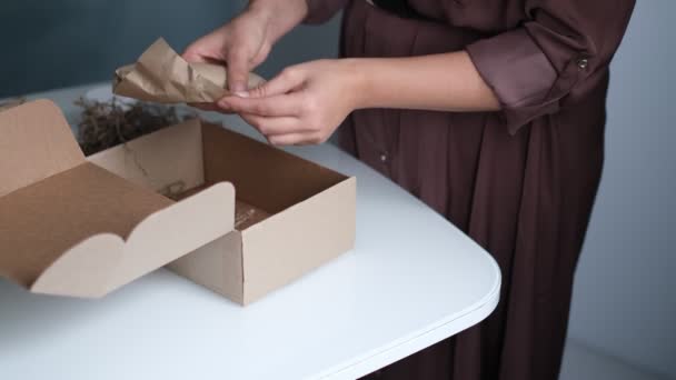 Frau öffnet Paket drinnen. Frau öffnet und packt Pappkartonpaket im heimischen Wohnzimmer aus. guter Lieferservice. — Stockvideo