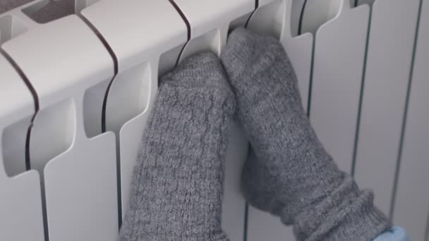 Conceito do início da estação de aquecimento. Mulher é quente meias de malha de lã perto de um aquecedor de casa no tempo frio de inverno. Usando aquecedor em casa no inverno. — Vídeo de Stock