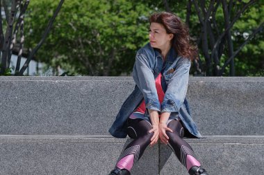 Elleri kasıklarına bastıran kadın karın altı, karın ağrısı çeken kadın hasta açık hava parkında.