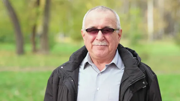 Senior man with a mustache in the park. portrait of a gray-haired man in a shirt and black jacket. — Stock Photo, Image