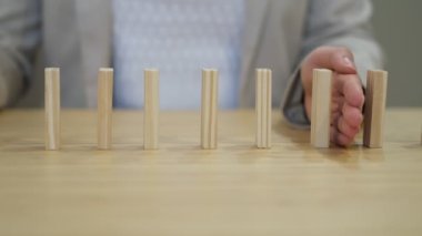 İş adamının eli ofis masasının üzerine renkli blokların düşmesini engelliyor. İş dünyasında domino etkisi.