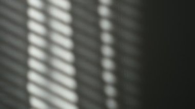 Sabah güneşi odayı aydınlatıyor, arka plan gölgeli. Duvardaki panjurların yansıması, çizgili gölgeler. Rüzgardan perdelerin yavaş hareketi