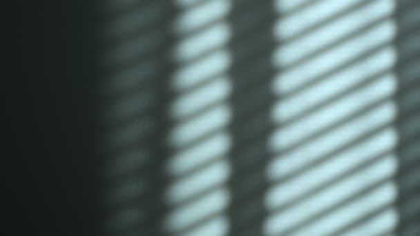 Ранкове сонячне світло освітлює кімнату, тло тіні накладається. відображення жалюзі на стіні, смугастих тінях. повільний рух штор з вітру — стокове відео