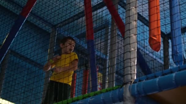 Little boy overcomes an obstacle course in a childrens sports center. cute boy having fun playing in large indoor play area for children. — Stock Video