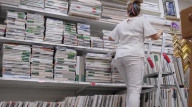 09.05.2021 - Moskova, Rusya - bir sanat mağazasındaki kadın sanatçı ürünleri seçiyor. Modern kadın süpermarketten alışveriş yapıyor..