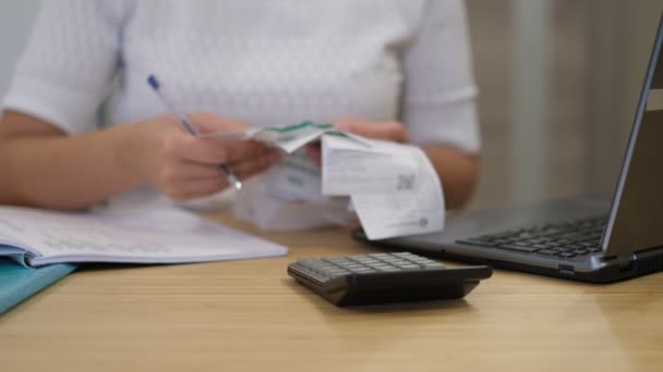 Frau benutzt Taschenrechner, um Rechnungen am Tisch im Büro zu berechnen. Frau mit Scheinen und Taschenrechner. — Stockvideo